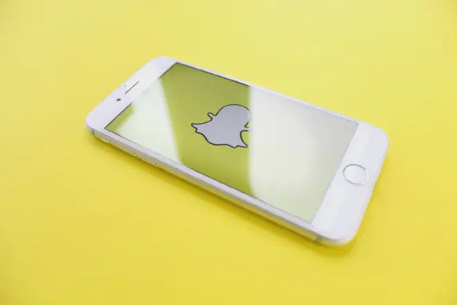 A person holding a phone with Snapchat app screen, demonstrating how to temporarily disable Snapchat